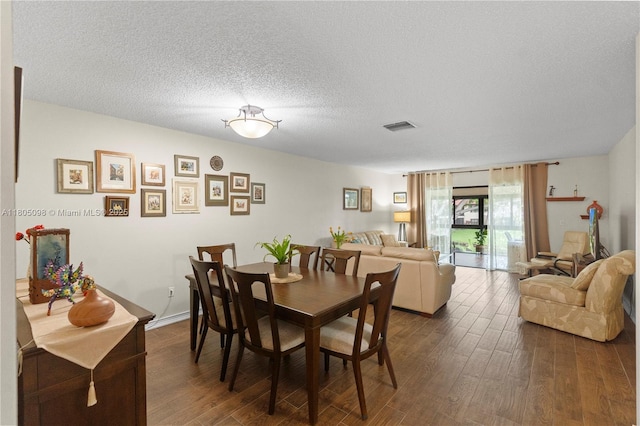 dining space featuring dark wood-style floors and a textured ceiling
