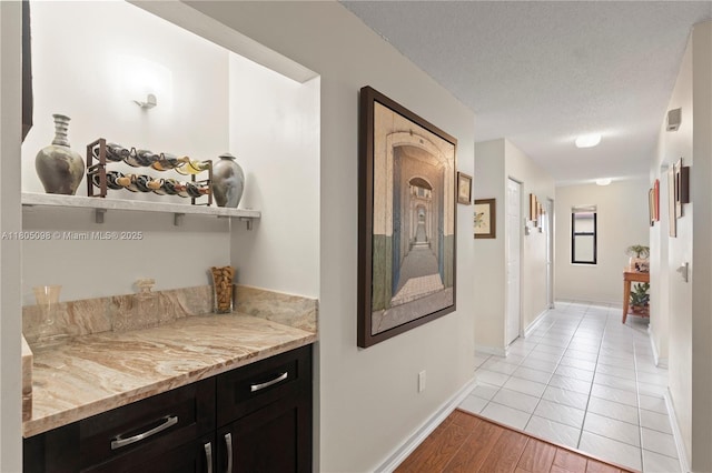 hall featuring baseboards, light wood finished floors, and a textured ceiling