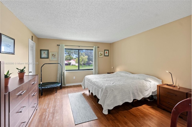 bedroom with light wood-style flooring, a textured ceiling, and baseboards