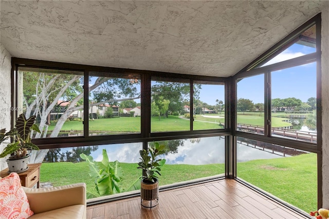 unfurnished sunroom with healthy amount of natural light, wood finished floors, a water view, and lofted ceiling