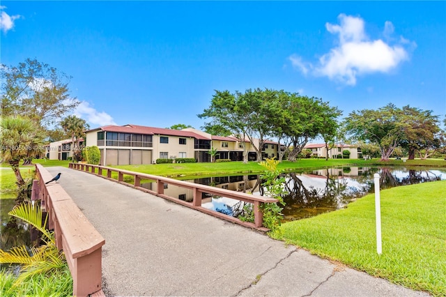 view of property's community featuring a water view, a yard, a residential view, and asphalt driveway