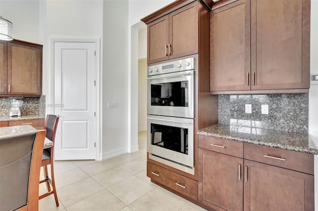 5474 S Sterling Ranch Cir, Davie, FL 33314 - kitchen with double oven, light stone countertops, tasteful backsplash, light tile patterned flooring, and baseboards