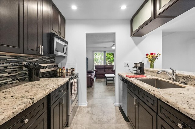 10772 La Placida Dr Unit 7-203, Coral Springs, FL 33065 - kitchen featuring appliances with stainless steel finishes, a sink, decorative backsplash, a ceiling fan, and light stone countertops