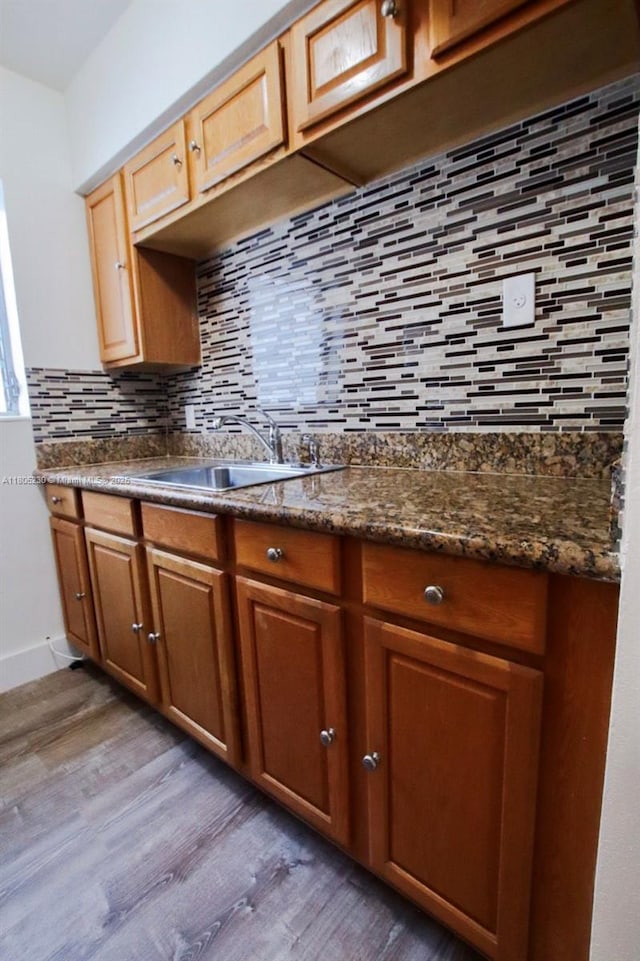 kitchen featuring light wood-style flooring, tasteful backsplash, and a sink