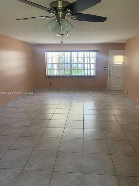 tiled spare room featuring a ceiling fan and a textured ceiling