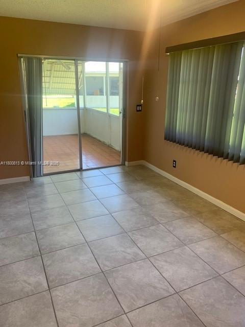 empty room with light tile patterned floors and baseboards