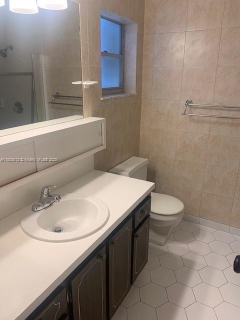 full bathroom featuring tile patterned flooring, vanity, toilet, a shower, and tile walls