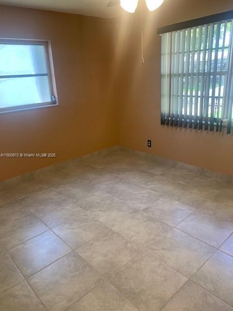 empty room featuring ceiling fan and tile patterned flooring