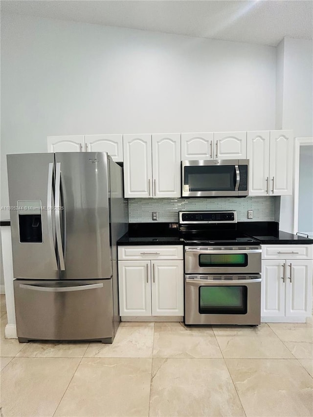 3480 Torremolinos Ave Unit A-33, Doral, FL 33178 - kitchen featuring appliances with stainless steel finishes, white cabinets, tasteful backsplash, and dark countertops