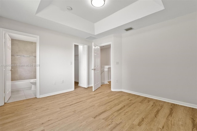 1458 SE 24th Ct Unit 353, Homestead, FL 33035 - unfurnished bedroom featuring a raised ceiling, light wood-style flooring, baseboards, a spacious closet, and connected bathroom