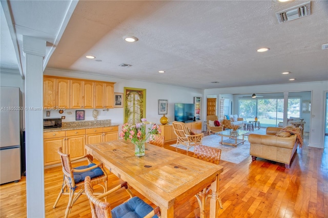dining space with a textured ceiling, light wood finished floors, and recessed lighting