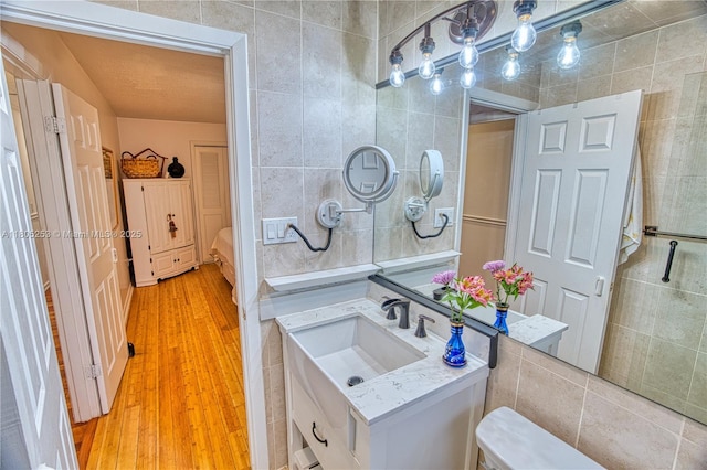 bathroom featuring tile walls, wood finished floors, and vanity