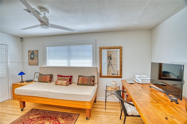 bedroom with a textured ceiling, light wood-type flooring, and ceiling fan