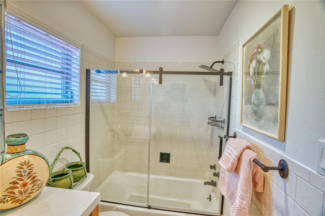 bathroom featuring tile walls, enclosed tub / shower combo, toilet, and vanity