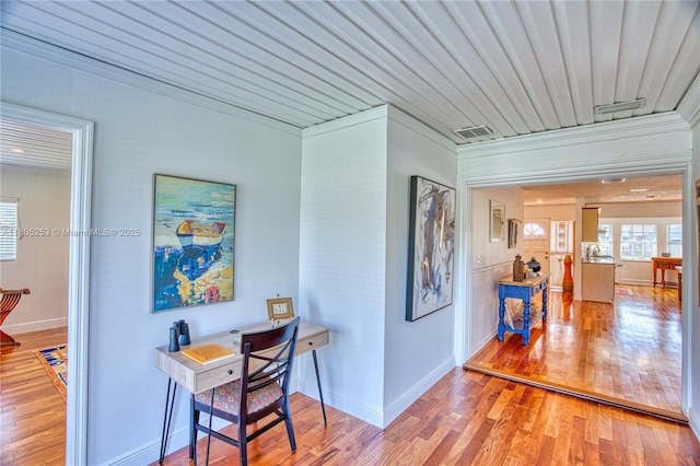 office area with wood finished floors, baseboards, and crown molding