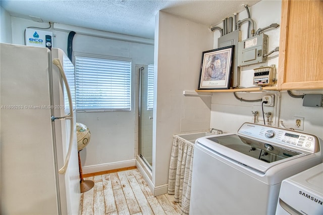laundry room with light wood-style flooring, a textured ceiling, and baseboards