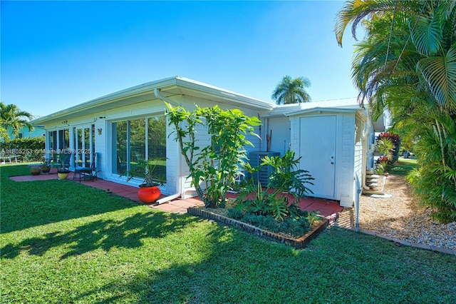 view of home's exterior featuring a lawn, concrete block siding, a storage unit, and an outbuilding