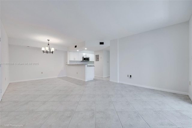 unfurnished living room with a chandelier, light tile patterned floors, and baseboards