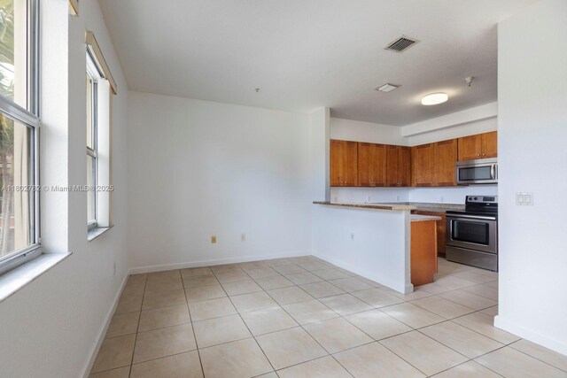 10022 NW 7th St Unit 206, Miami, FL 33172 - kitchen with stainless steel appliances, brown cabinets, a peninsula, and light tile patterned floors
