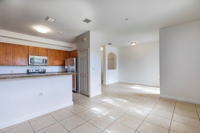 10022 NW 7th St Unit 206, Miami, FL 33172 - kitchen with stainless steel appliances, brown cabinetry, light tile patterned floors, and baseboards