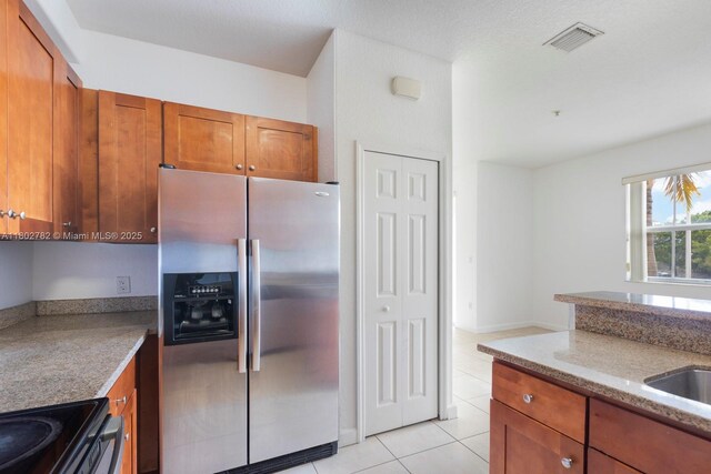 10022 NW 7th St Unit 206, Miami, FL 33172 - kitchen featuring stainless steel fridge, brown cabinets, light tile patterned flooring, light stone counters, and black electric range oven