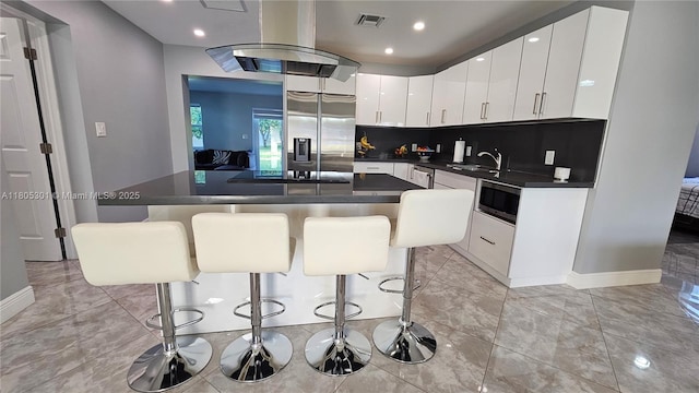 4651 SW 19th St, Fort Lauderdale, FL 33317 - kitchen with appliances with stainless steel finishes, dark countertops, a kitchen island, a kitchen breakfast bar, and white cabinets