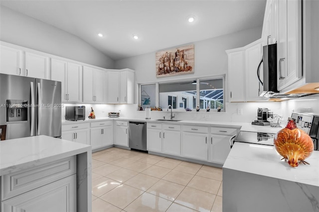kitchen with appliances with stainless steel finishes, a sink, white cabinets, light tile patterned floors, and lofted ceiling