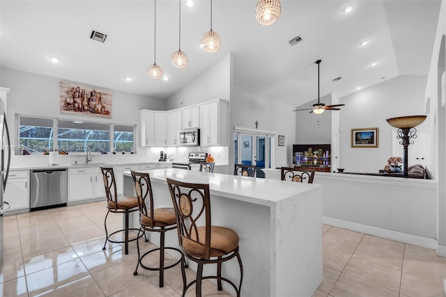 kitchen featuring appliances with stainless steel finishes, high vaulted ceiling, a center island, a breakfast bar, and light tile patterned flooring