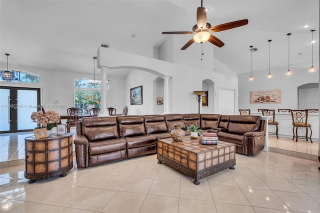 living area featuring arched walkways, a ceiling fan, decorative columns, high vaulted ceiling, and light tile patterned floors