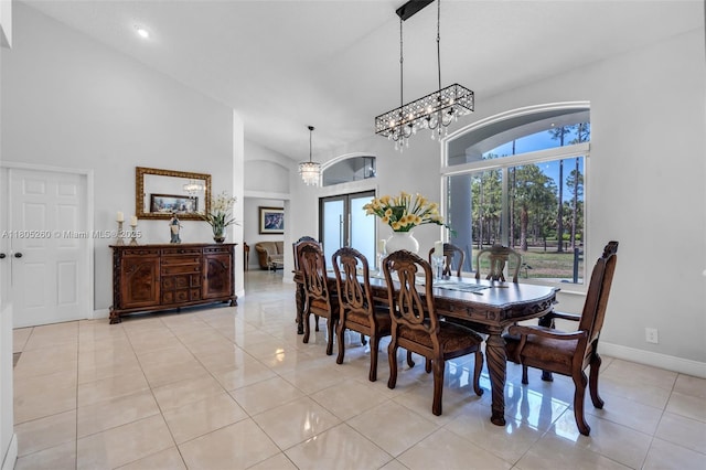 dining space featuring high vaulted ceiling, light tile patterned floors, baseboards, and a chandelier