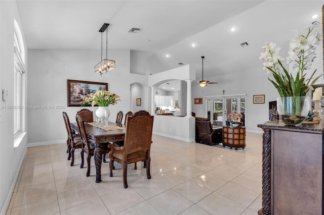 dining space with decorative columns, arched walkways, light tile patterned floors, baseboards, and a ceiling fan