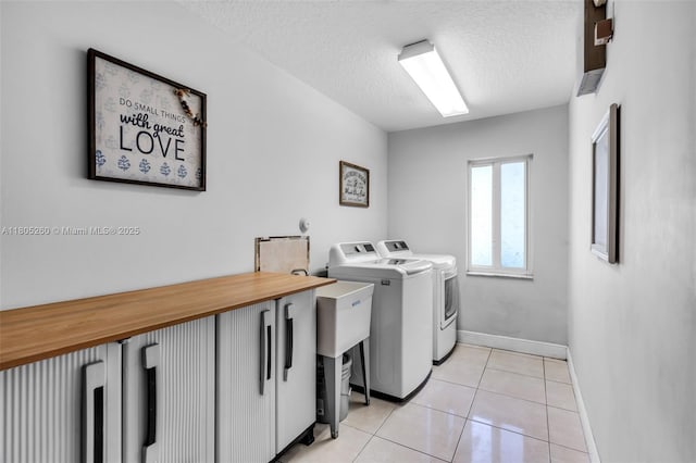 washroom with washer and clothes dryer, a textured ceiling, baseboards, and light tile patterned floors