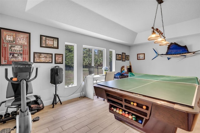 recreation room with light wood-style flooring, baseboards, and a raised ceiling