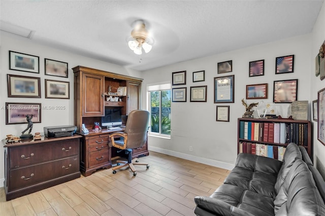 office with a ceiling fan, baseboards, light wood-style floors, and a textured ceiling