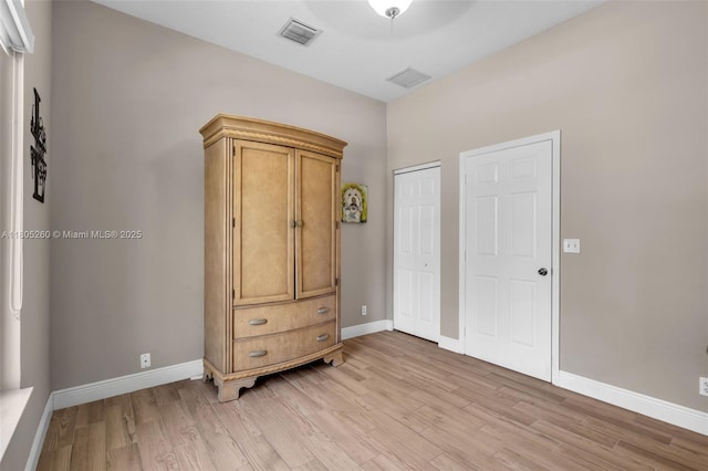 bedroom with light wood-type flooring, baseboards, and a closet