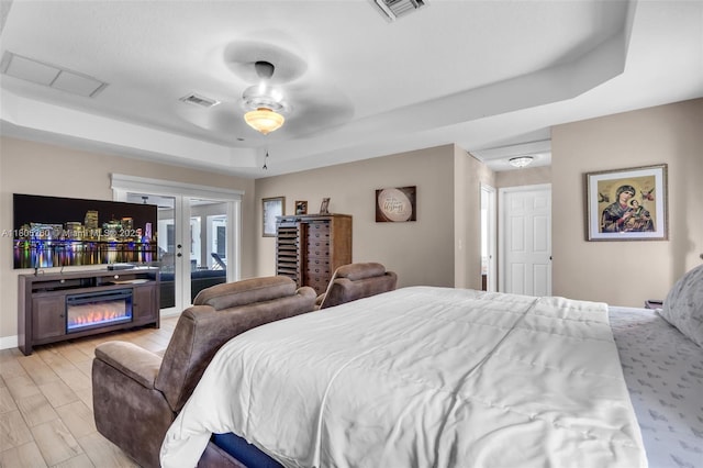 bedroom featuring a raised ceiling, ceiling fan, and baseboards