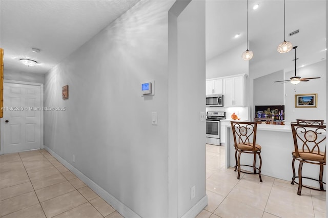 hallway with light tile patterned floors, high vaulted ceiling, and baseboards