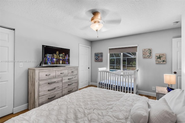 bedroom with baseboards, wood finished floors, a textured ceiling, and a ceiling fan