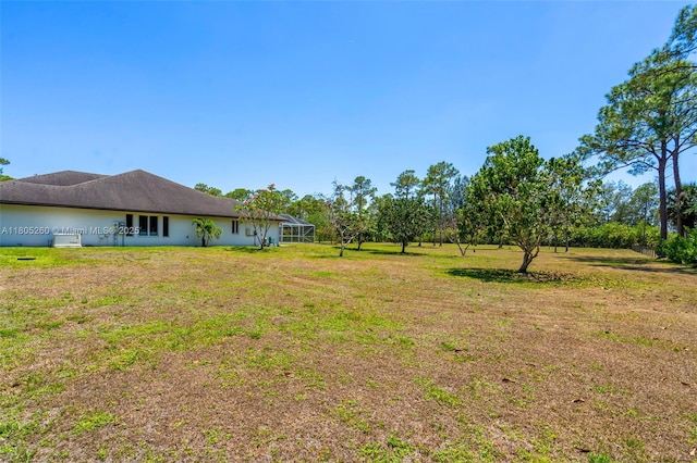 view of grassy yard with glass enclosure