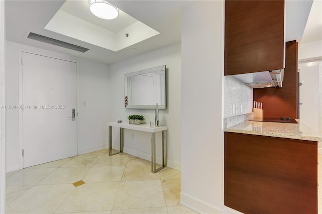 1830 S Ocean Dr Unit 3804, Hallandale Beach, FL 33009 - kitchen featuring decorative backsplash, light stone counters, a tray ceiling, baseboards, and light tile patterned floors