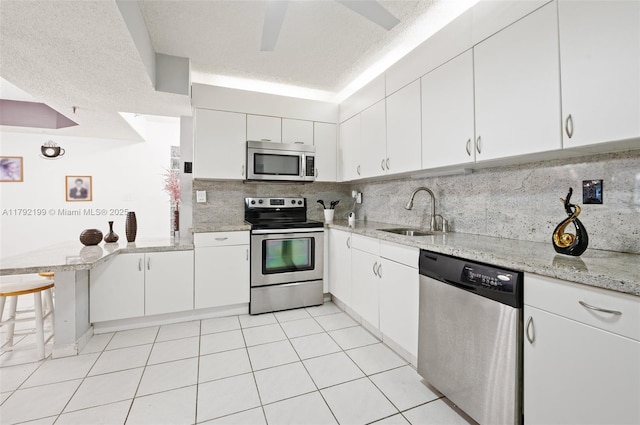9341 Collins Ave Unit 1204, Surfside, FL 33154 - kitchen with appliances with stainless steel finishes, a sink, white cabinets, and decorative backsplash