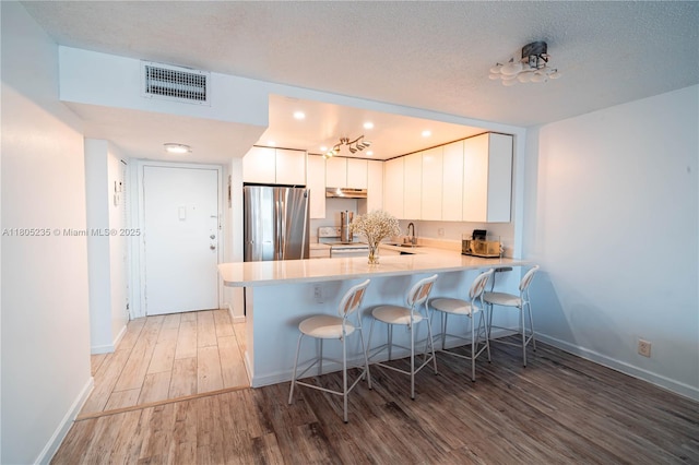 1817 S Ocean Dr Unit 0918, Hallandale Beach, FL 33009 - kitchen featuring freestanding refrigerator, light wood-style flooring, a peninsula, a kitchen bar, and recessed lighting