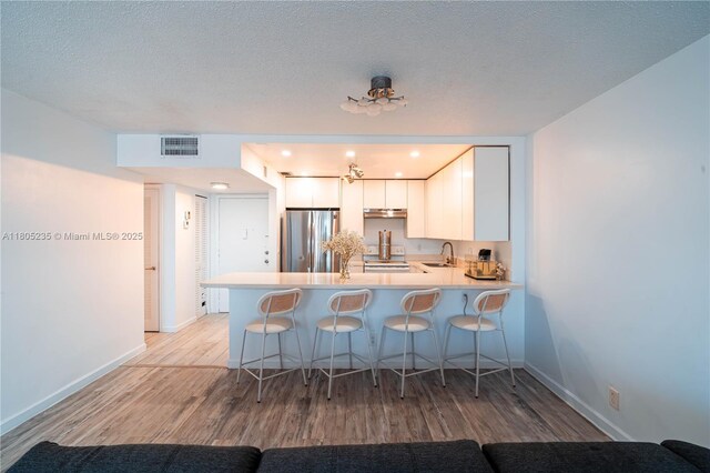 1817 S Ocean Dr Unit 0918, Hallandale Beach, FL 33009 - kitchen featuring freestanding refrigerator, a sink, a peninsula, light wood finished floors, and a kitchen bar