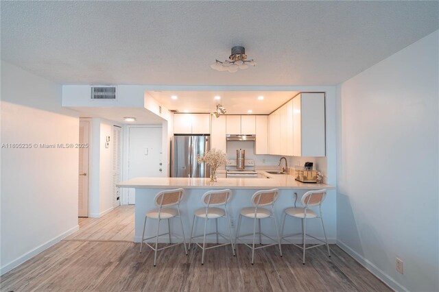 1817 S Ocean Dr Unit 0918, Hallandale Beach, FL 33009 - kitchen featuring freestanding refrigerator, a peninsula, light wood-style floors, a sink, and a breakfast bar