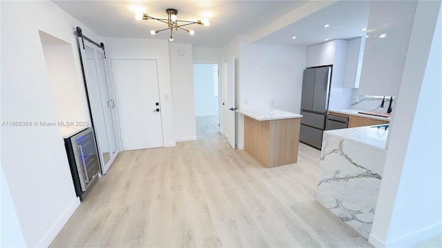 701 Collins Ave Unit 1F, Miami Beach, FL 33139 - kitchen with modern cabinets, freestanding refrigerator, light wood-style flooring, light stone countertops, and a barn door