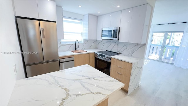 701 Collins Ave Unit 1F, Miami Beach, FL 33139 - kitchen featuring stainless steel appliances, modern cabinets, backsplash, light stone counters, and recessed lighting