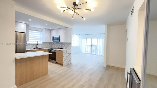 701 Collins Ave Unit 1F, Miami Beach, FL 33139 - kitchen featuring appliances with stainless steel finishes, modern cabinets, a chandelier, light countertops, and decorative backsplash