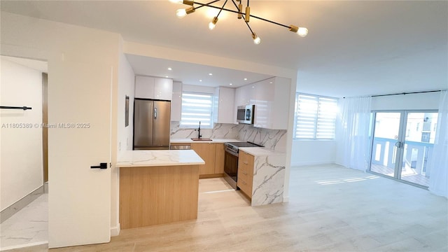 701 Collins Ave Unit 1F, Miami Beach, FL 33139 - kitchen with appliances with stainless steel finishes, modern cabinets, light wood-type flooring, and tasteful backsplash