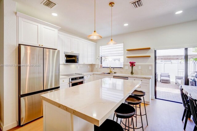 10602 W 33rd Way, Hialeah, FL 33018 - kitchen featuring appliances with stainless steel finishes, healthy amount of natural light, light wood finished floors, a breakfast bar area, and recessed lighting