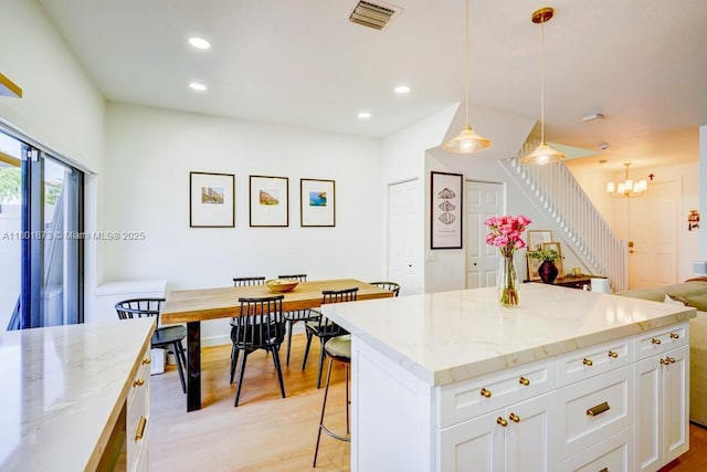 10602 W 33rd Way, Hialeah, FL 33018 - kitchen featuring light wood-type flooring, light stone countertops, white cabinets, a kitchen bar, and recessed lighting